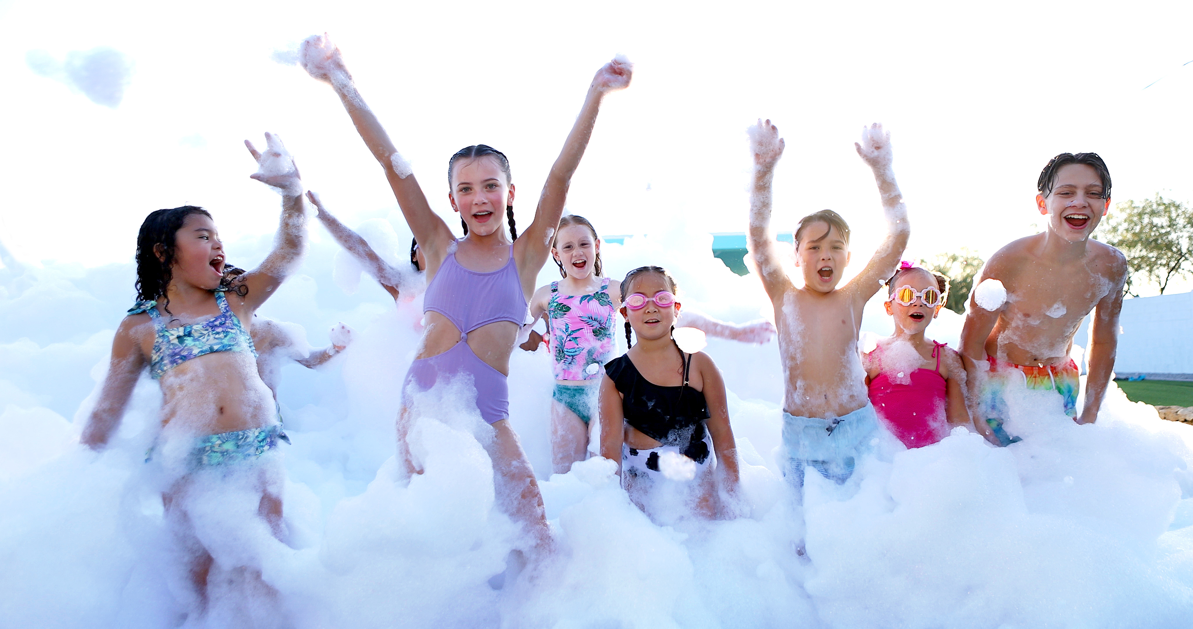 Group of kids cheering with arms raised in giant foam