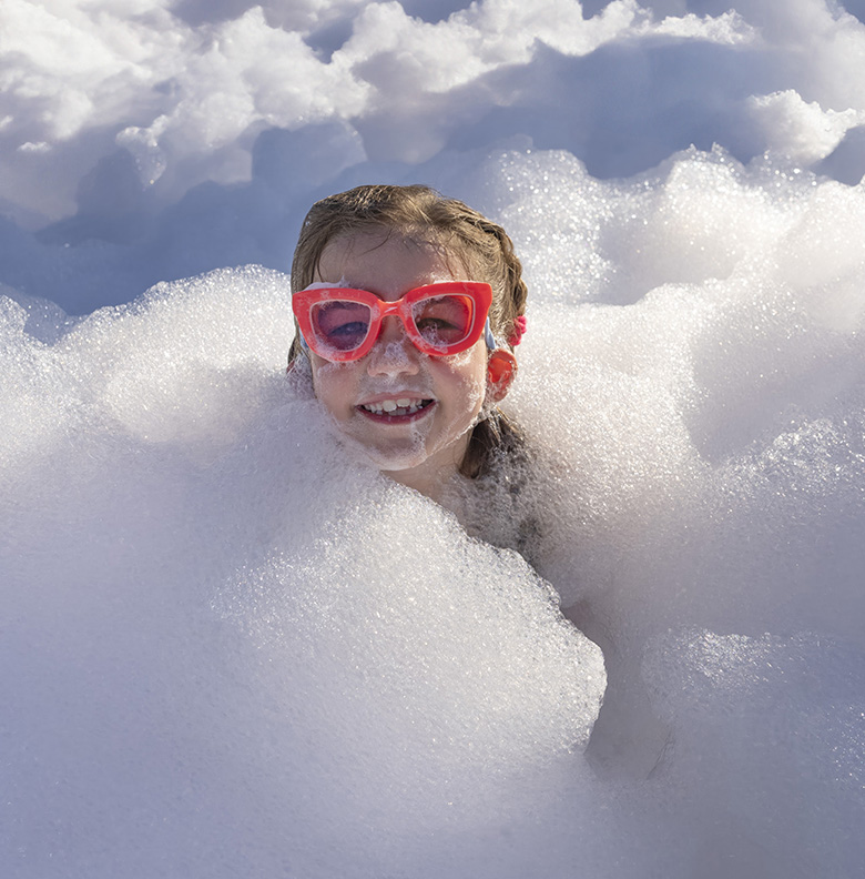Happy kid peeking out of foam mountain